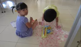 The children unwrapping their gifts - pencils, notebooks, coloring books, suckers and more