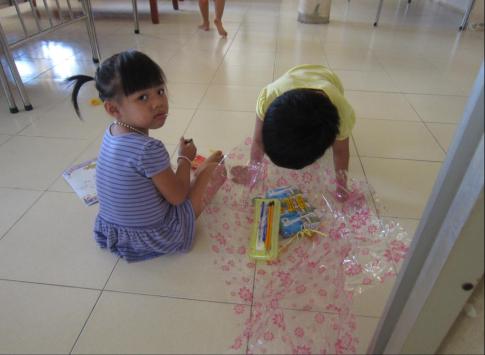 The children unwrapping their gifts - pencils, notebooks, coloring books, suckers and more