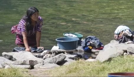 A woman washes her clothes in the river