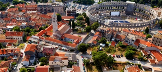 Admire the distinctive red roofs and Roman ruins of Pula