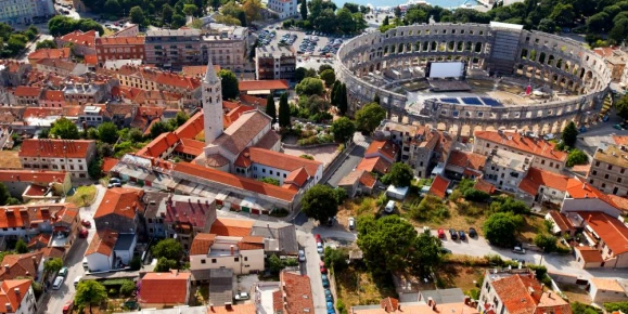 Admire the distinctive red roofs and Roman ruins of Pula