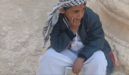 Syrian boy reluctantly selling postcards