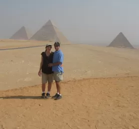 A couple poses in front of the pyramids.