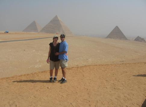 A couple poses in front of the pyramids.