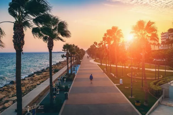 Limassol promenade or embankment at sunset. Aerial view of famous Cyprus alley with palms and walking people.