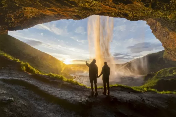 Couple standing beneath waterfall in Iceland