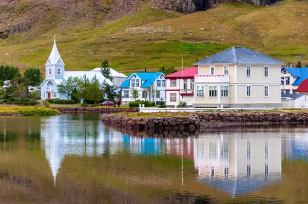 Cityscape view of the town of Seydisfjordur, Iceland and its reflection on the water of sea fjord.
