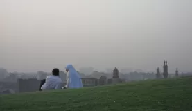 A couple sits on a hill to admire the view.