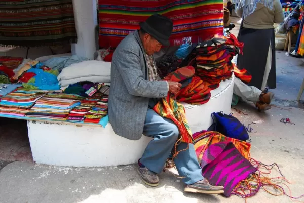 An Ecuadorian man sewing sacks and bags for sale.