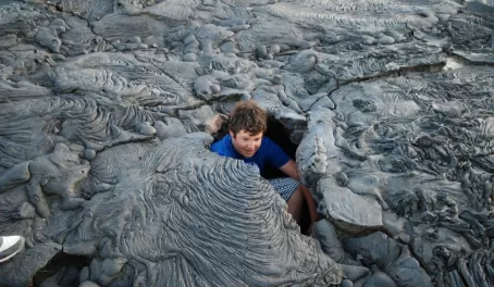 Teenage traveler exploring a lava tube in the Galapagos