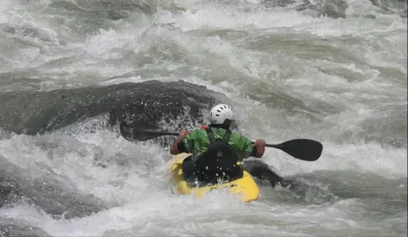 Saftey Kayaker flipping in front of rock