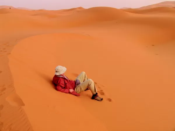 A man rests on the bright red sand of Africa.