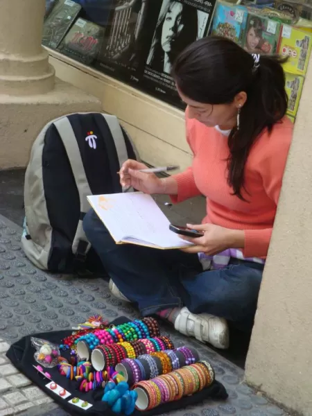 A young woman selling trinkets while doing her homework