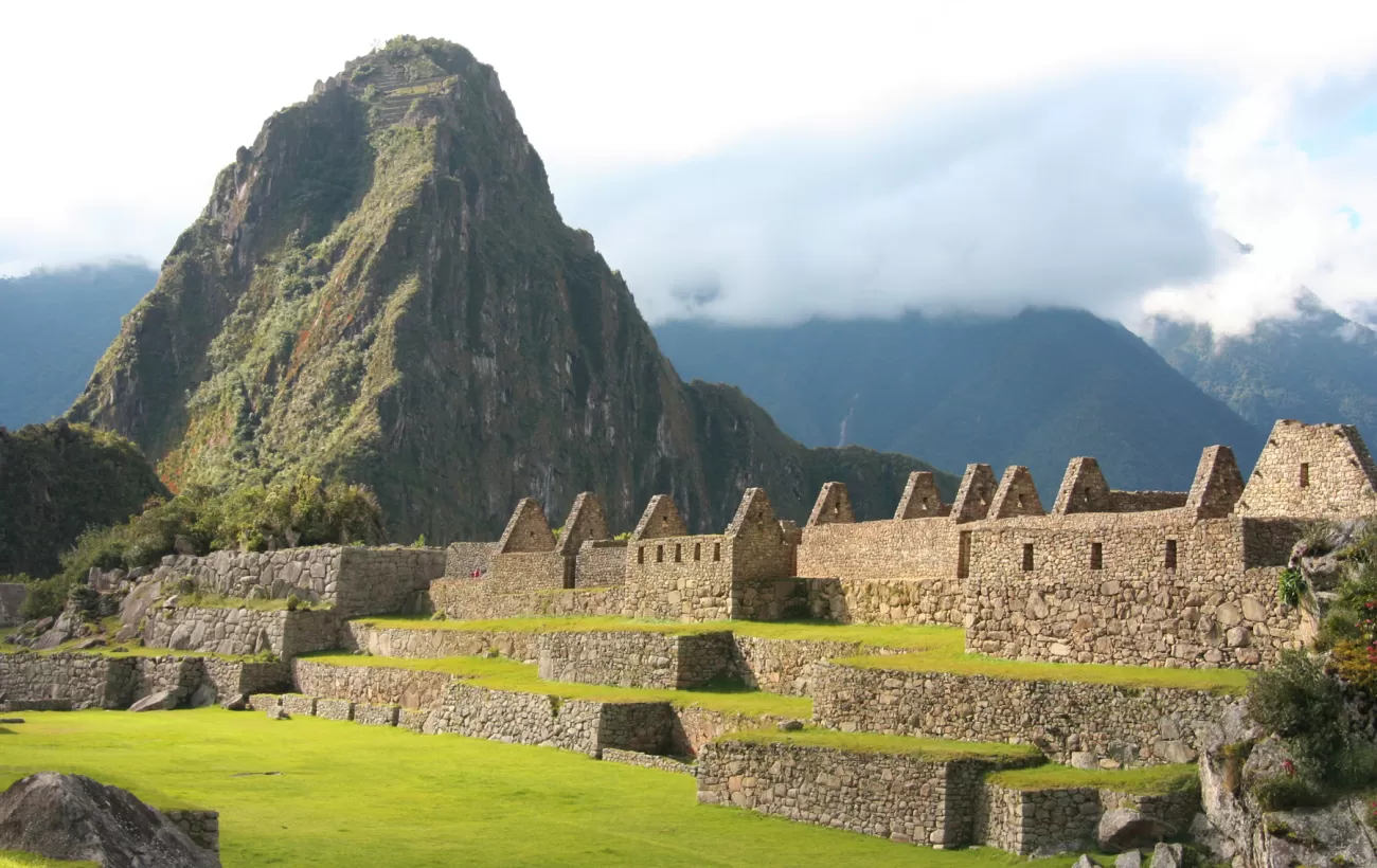 Huayna Picchu rises high behind the Machu Picchu ruins during your Peru tour