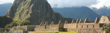 Huayna Picchu rises high behind the Machu Picchu ruins during your Peru tour