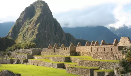 Huayna Picchu rises high behind the Machu Picchu ruins during your Peru tour