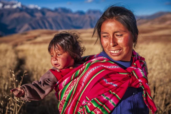 Peruvian woman near Cusco carrying child on her back.