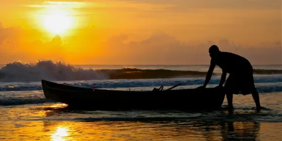 A local fisherman pulls his boat ashore at sunset in Costa Rica