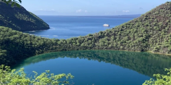 Vantage point of the saltwater volcanic crater lagoon, Darwin Lake and the Santa Cruz II anchored in the distance on the volcanic caldera, Tagus Cove.