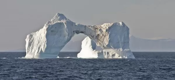 An iceberg bridge floats on the chilly Arctic waters