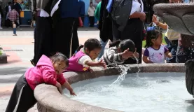 Local children playing in a fountain in Quito