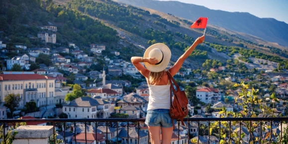 Young female with albanian flag enjoying panoramic view of Gjirokaster city