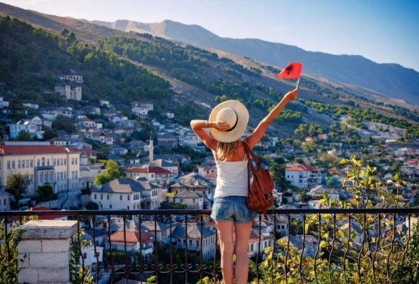 Young female with albanian flag enjoying panoramic view of Gjirokaster city