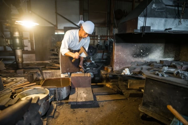 Japanese blacksmith hammers hot steel in his forge