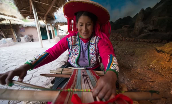 Woman weaving on a backstrap loom in traditional attire in Sacred Valley.