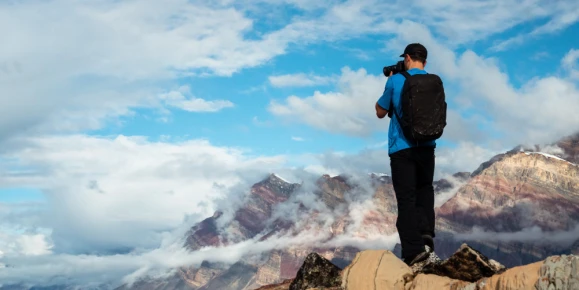 A photographer capturing the stunning landscape of Greenland, known for its dramatic mountainous terrain and glaciers