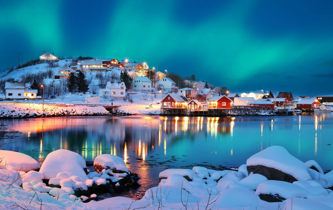 Dramatic evening cityscape of Reine town with Northern Lights