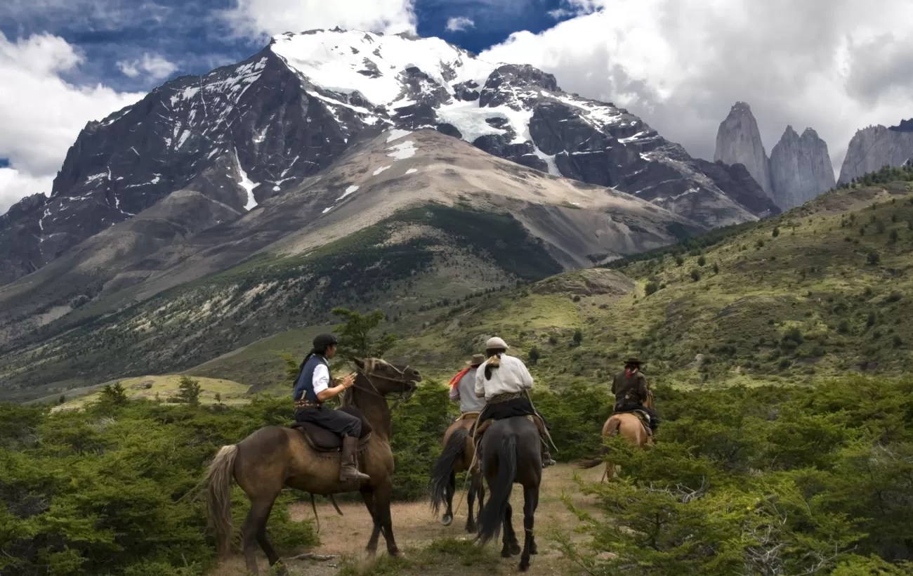 Chilean huasos riding rowards the towers in Torres del Paine