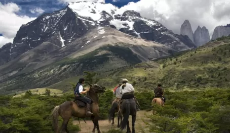 Chilean huasos riding rowards the towers in Torres del Paine
