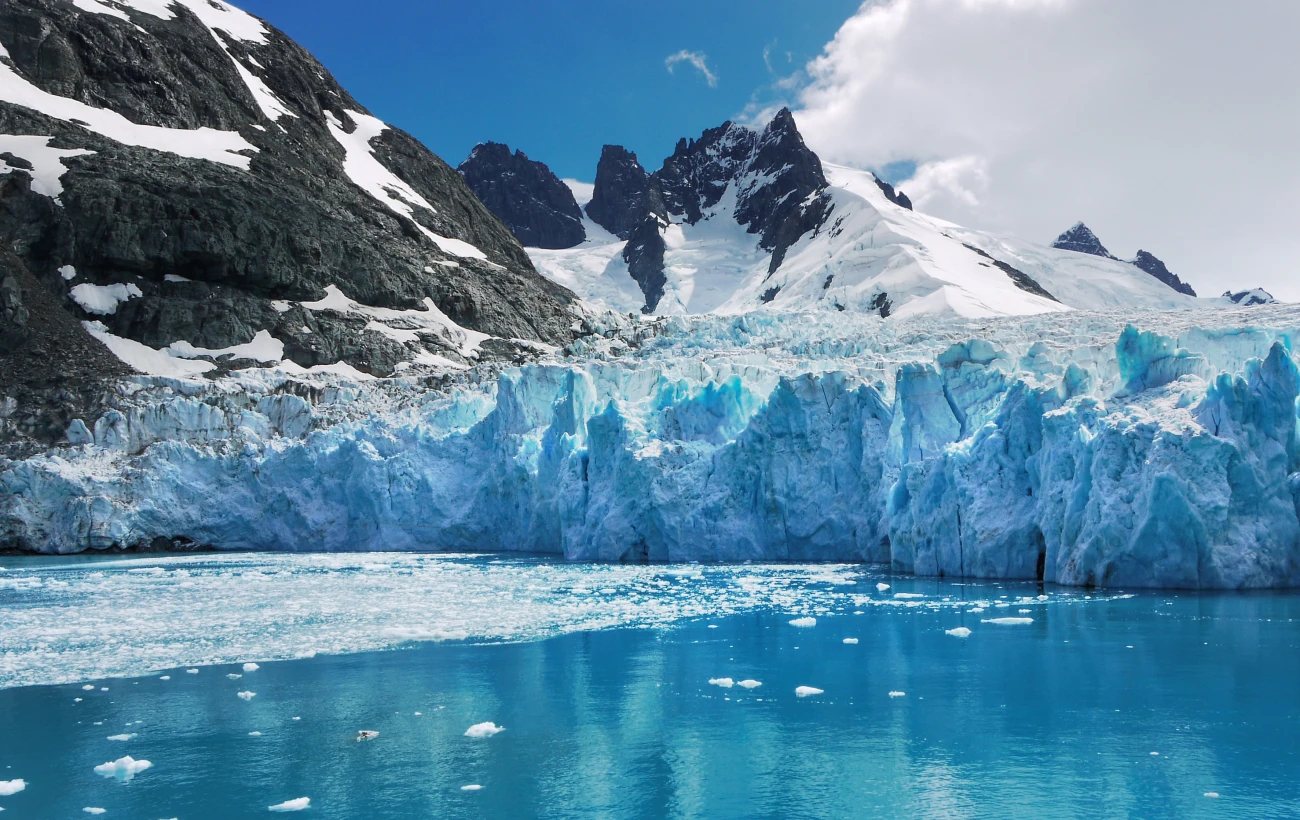 Blue and turquoise color ice of glacier face and reflections in calm water of Drygalski Fjord, South Georgia Island.