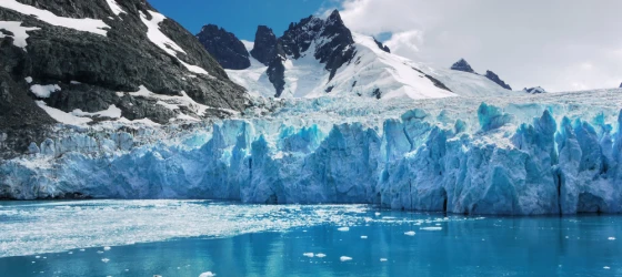 Blue and turquoise color ice of glacier face and reflections in calm water of Drygalski Fjord, South Georgia Island.