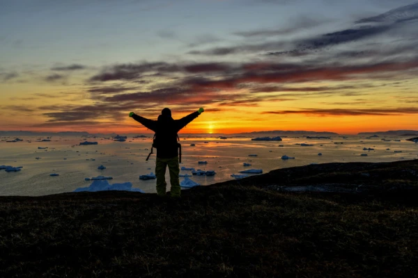 Traveler enjoying the sunset and the scenery in Greenland