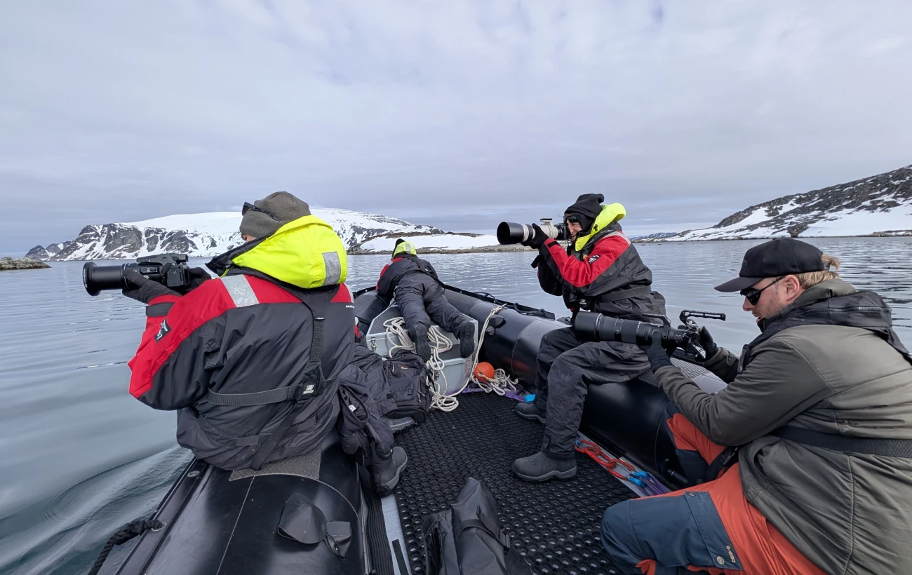 Travelers taking photos in Arctic while riding in a zodiac.