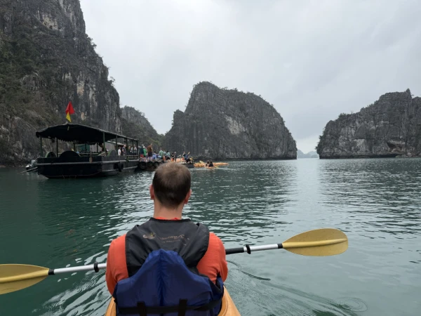 Travelers doing kayaking adventure in Ha Long Bay facing the limestone island