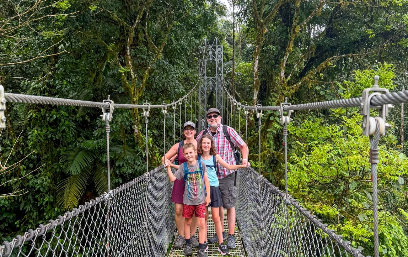 Erin and her family exploring Mistico Arenal Hanging Bridges Park in Costa Rica, walking across suspension bridges and forest trails surrounded by lush tropical vegetation near Arenal Volcano.