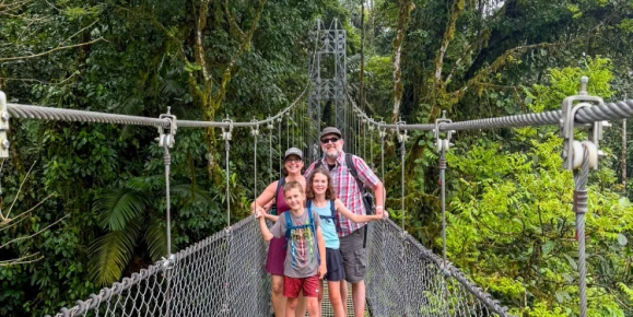 Erin and her family exploring Mistico Arenal Hanging Bridges Park in Costa Rica, walking across suspension bridges and forest trails surrounded by lush tropical vegetation near Arenal Volcano.