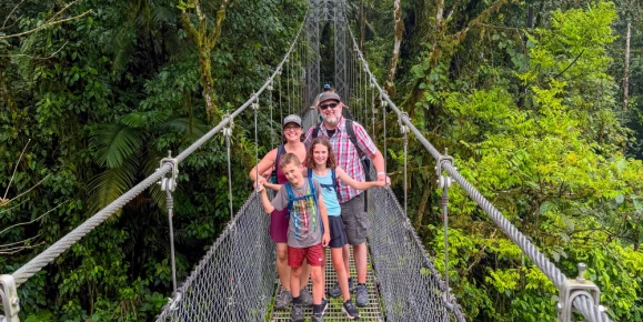 Erin and her family exploring Mistico Arenal Hanging Bridges Park in Costa Rica, walking across suspension bridges and forest trails surrounded by lush tropical vegetation near Arenal Volcano.