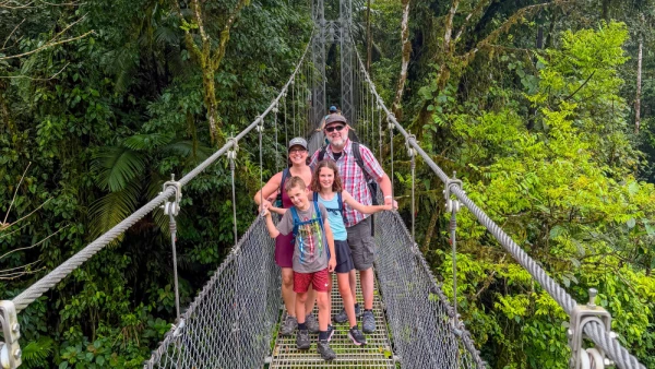 Erin and her family exploring Mistico Arenal Hanging Bridges Park in Costa Rica, walking across suspension bridges and forest trails surrounded by lush tropical vegetation near Arenal Volcano.