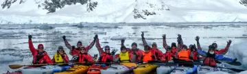 A group of kayakers pose in the icy waters of Antarctica.