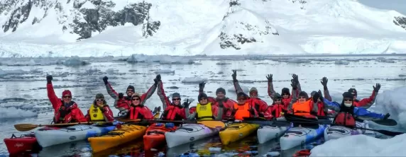 A group of kayakers pose in the icy waters of Antarctica.