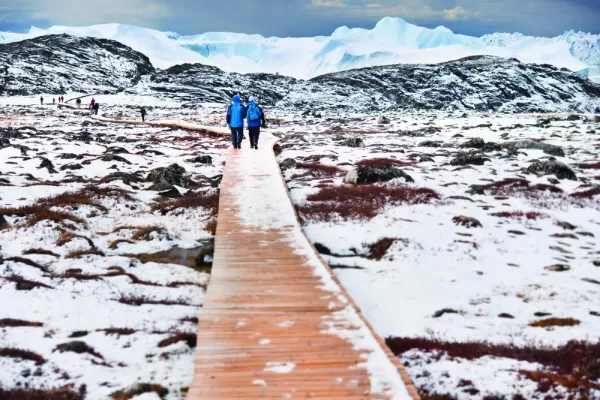 Travelers walking on a boardwalk in the winter arctic tundra.