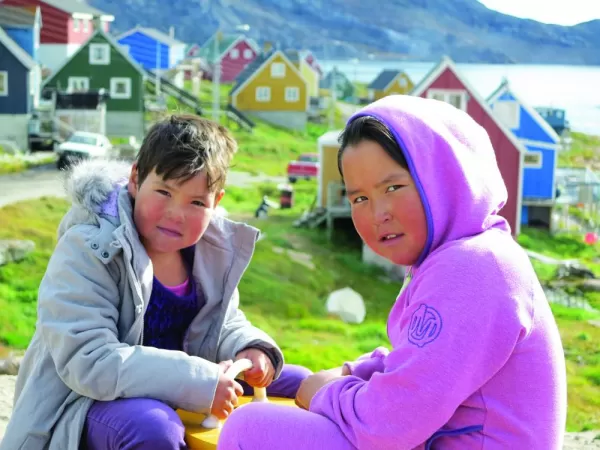 Local girls sit in front of colorful houses in their village.