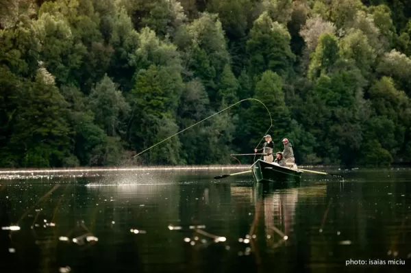 Two fly fisherman attempt a catch in their boat.
