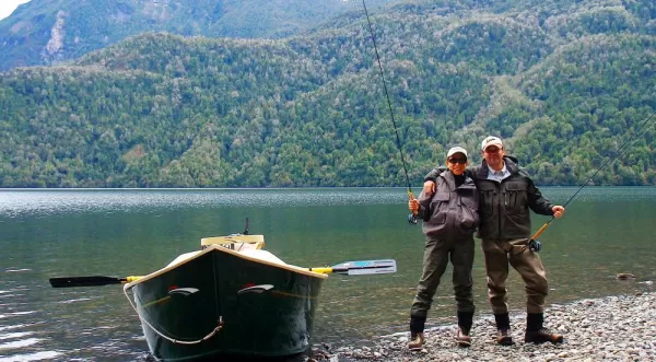 Two fly fisherman pose next to their boat.