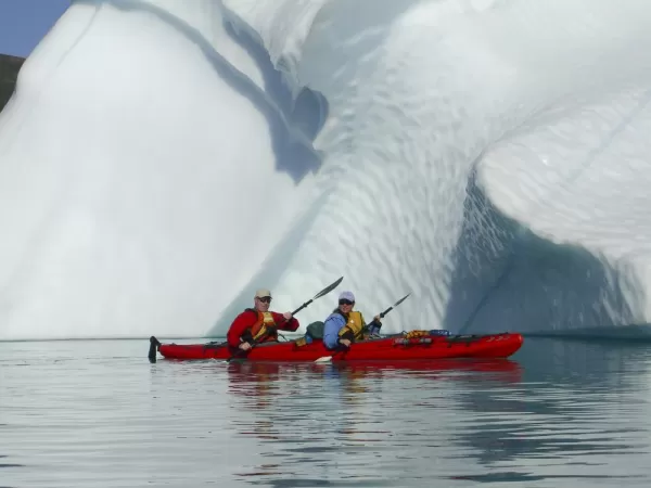 Kayaking in front of a huge iceberg.