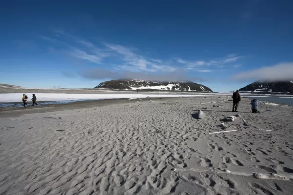 Travelers walking across the beaches of Spitsbergen.